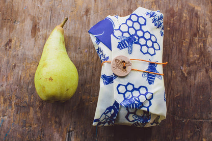 Bee's Wrap Bears and Bees Print Sandwich Wrap wrapped up next to a pear for scale